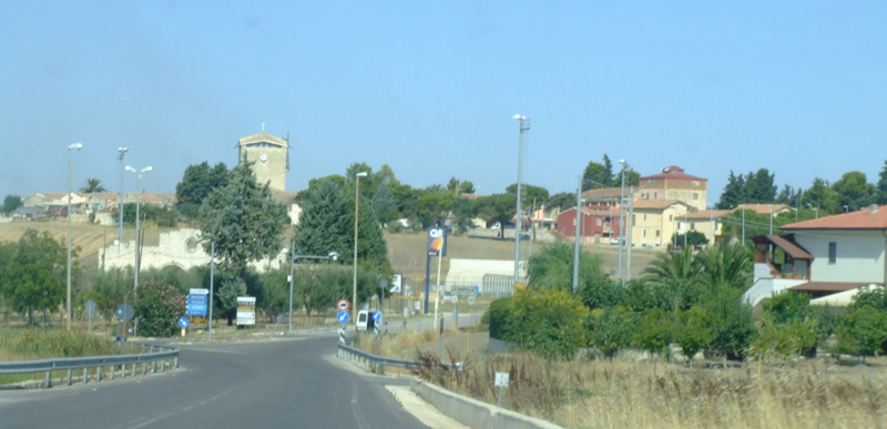 La torre del complesso parrocchiale, il centro civico e le parti  orientali del villaggio, ripresi dalla strada per Matera