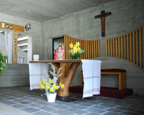 Altare della cappella, gi utilizzato nella prima chiesa provvisoria, ricavato da un tronco di melo cresciuto nel podere dell'Istituto Buon Pastore; alle spalle, la vetrata del Buon Pastore