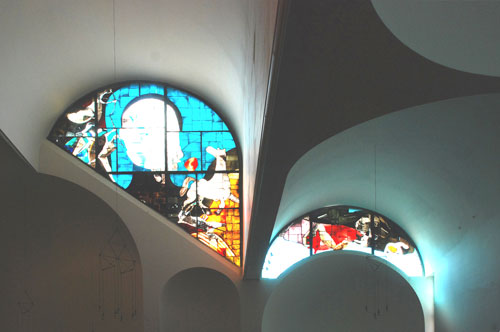 Le vetrate in controfacciata: il Cantico dei Cantici (sopra la porta d'ingresso ordinaria) e i Vizi (sopra il battistero), disegnate da Enrico Castiglioni.